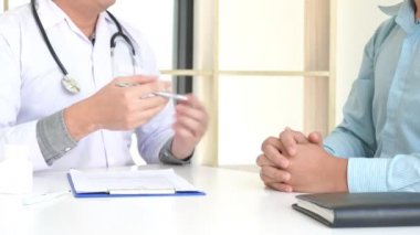 Hastanın hasta semptomlarını açıklayan bir erkek doktoru dikkatle dinlediği ya da muayenede birlikte evrak işlerini tartışırken soru sorduğu 4K videosu.
