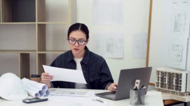 Bayan mühendis ofiste planlar üzerinde çalışıyor.