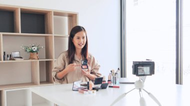 Güzel Asyalı kadın profesyonel güzellik vlog 'u veya blog yazarı kozmetik sunar ve video kaydı için ön kameraya makyaj uygular