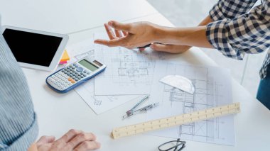 Mühendis El Çizimi Mavi Yazdırma Planı. Mimari ekipmanlarla birlikte modern bir ofiste, mimari planlar üzerinde kat planlarını tartışıyorlar.