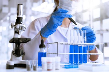 Laboratuvarda beyaz önlükle araştırma yapan bilim adamları eldivenleri analiz ediyor, test tüpleri örneklerine bakıyor, biyoteknoloji kavramına bakıyor..