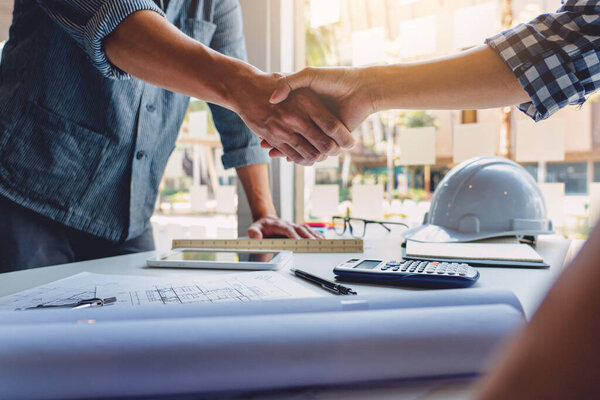 Architect and engineer construction workers shaking hands while working for teamwork and cooperation concept after finish an agreement in the office construction site, success collaboration concept