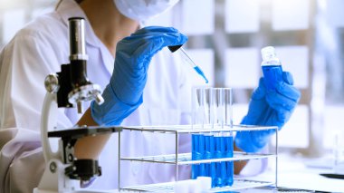 Laboratuvarda beyaz önlükle araştırma yapan bilim adamları eldivenleri analiz ediyor, test tüpleri örneklerine bakıyor, biyoteknoloji kavramına bakıyor..