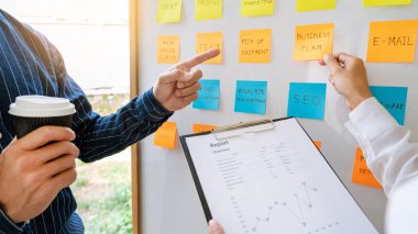 İş adamları, çalışma öncelikleri üzerine yorum yapan ve beyin fırtınası yapan yapış yapış notlar düzenliyor.