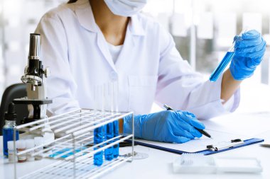 Laboratuvarda beyaz önlükle araştırma yapan bilim adamları eldivenleri analiz ediyor, test tüpleri örneklerine bakıyor, biyoteknoloji kavramına bakıyor..