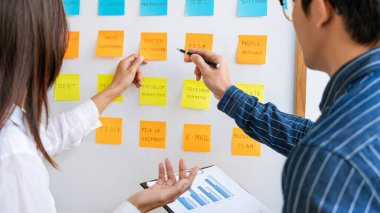 İş adamları, çalışma öncelikleri üzerine yorum yapan ve beyin fırtınası yapan yapış yapış notlar düzenliyor.