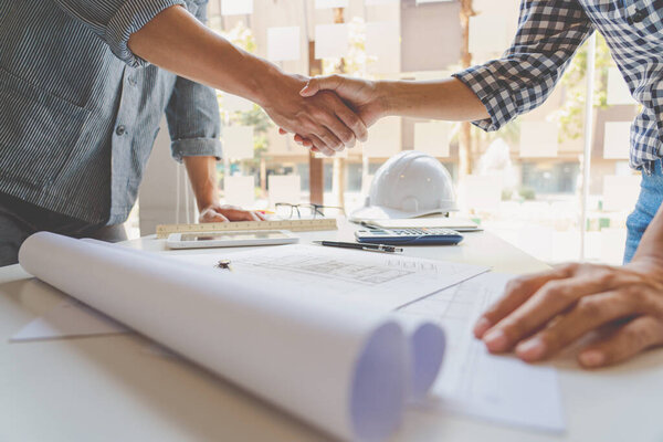 Architect and engineer construction workers shaking hands while working for teamwork and cooperation concept after finish an agreement in the office construction site, success collaboration concept