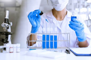 Laboratuvarda beyaz önlükle araştırma yapan bilim adamları eldivenleri analiz ediyor, test tüpleri örneklerine bakıyor, biyoteknoloji kavramına bakıyor..