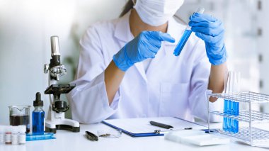 Laboratuvarda beyaz önlükle araştırma yapan bilim adamları eldivenleri analiz ediyor, test tüpleri örneklerine bakıyor, biyoteknoloji kavramına bakıyor..