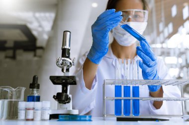Laboratuvarda beyaz önlükle araştırma yapan bilim adamları eldivenleri analiz ediyor, test tüpleri örneklerine bakıyor, biyoteknoloji kavramına bakıyor..
