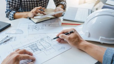 Mühendis El Çizimi Mavi Yazdırma Planı. Mimari ekipmanlarla birlikte modern bir ofiste, mimari planlar üzerinde kat planlarını tartışıyorlar.