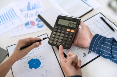 Toplantı ve başarılı takım çalışması konseptinde finansal belge grafikleri ve grafiklerini analiz eden yeni bir başlangıç projesiyle ofis masasında plan ile çalışan iş ekibi