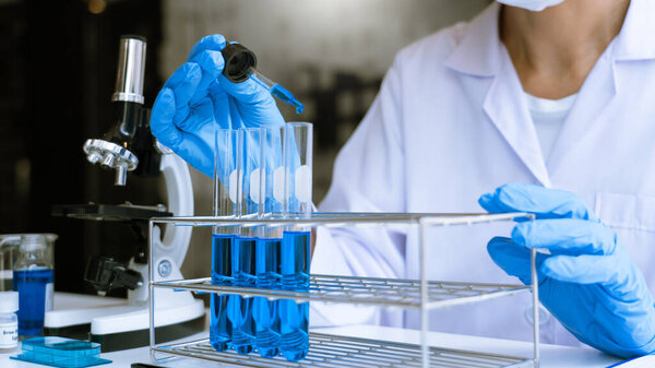 Ученые в лабораторном халате и защитной одежде работают с исследованиями или проводят исследования с помощью пробирки в эксперименте, лаборатории и концепции развития.