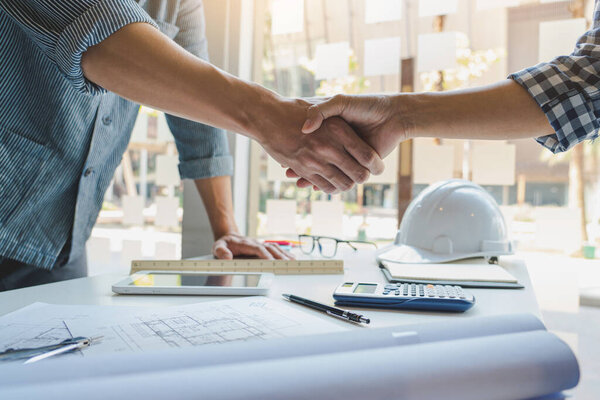 Architect and engineer construction workers shaking hands while working for teamwork and cooperation concept after finish an agreement in the office construction site, success collaboration concept