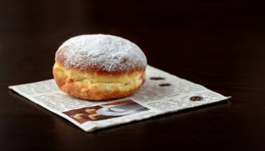 Karanlık bir arka plan ile gazete peçeteye tek çörek taze pişmiş