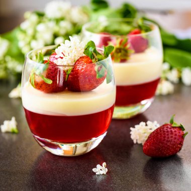 İtalyan bahar tatlı panna cotta çilek ve çiçeklerle pembe bir artalan üzerinde