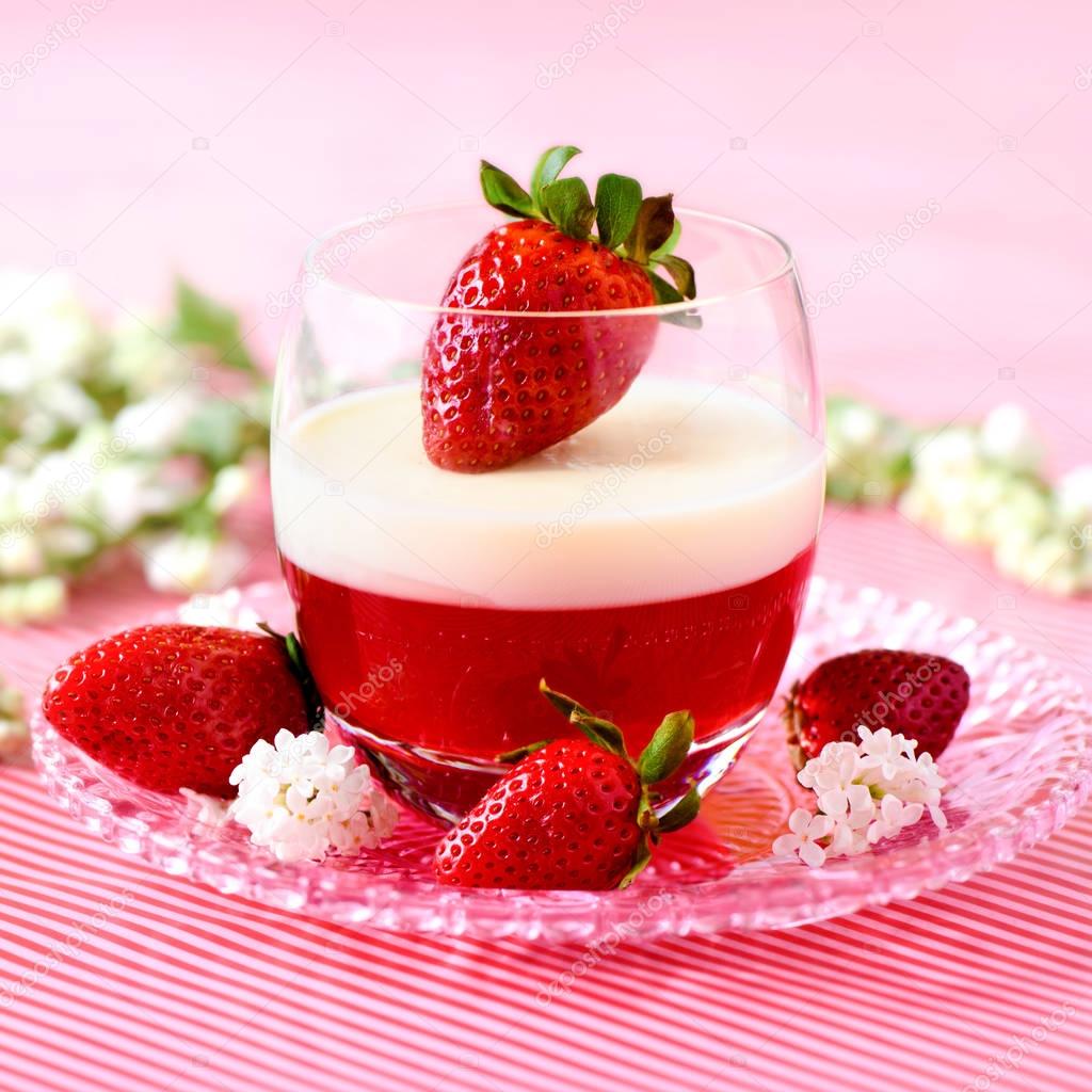 Italian spring dessert panna cotta with strawberries and flowers on a pink backgound