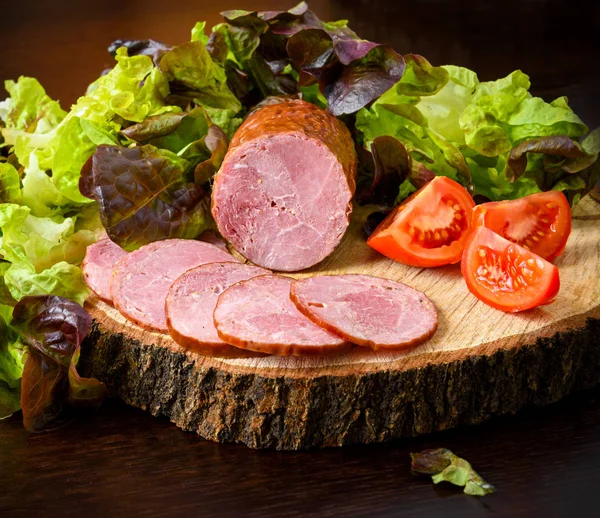 Makkara, kinkku tomaattien ja salaatin kanssa puulaudalla, kanto — kuvapankkivalokuva