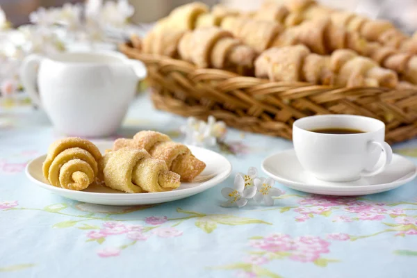 De nombreux croissants sur une table aux fleurs printanières — Photo