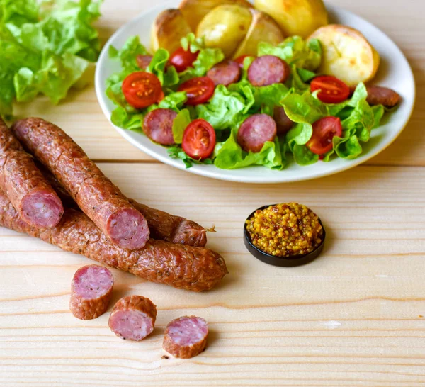 Копченая колбаса с салатом из овощей на деревянной доске — стоковое фото