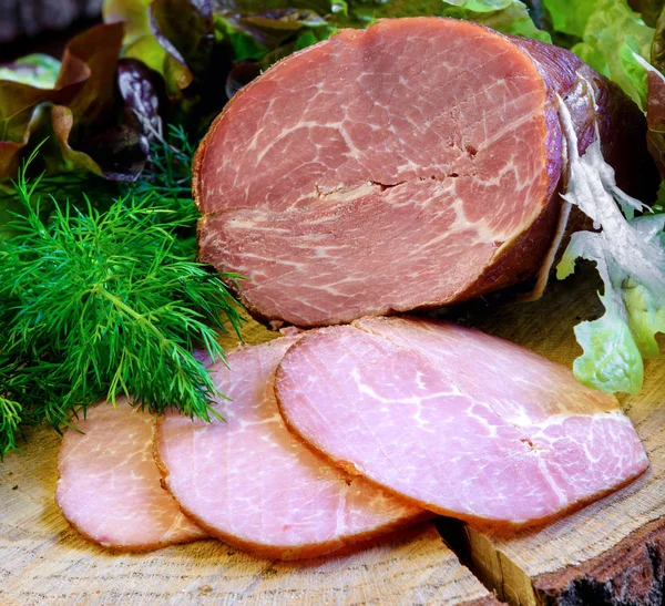 Smoked ham with herbs (dill, lettuce) on wooden board — Stock Photo, Image
