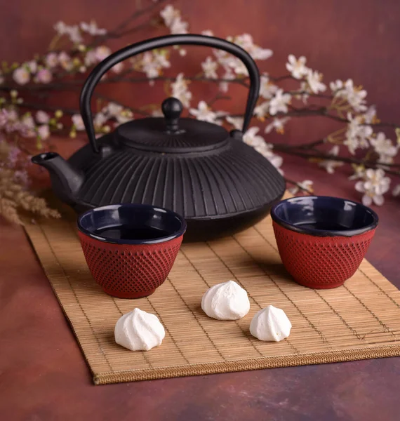 濃い赤色の背景にカップ ケーキ 花を入れた中国や日本のティーポット — ストック写真