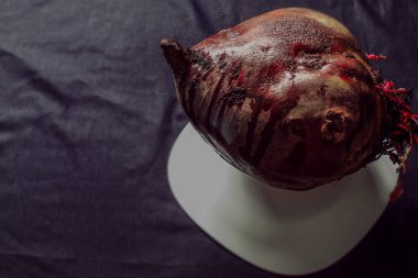 Pancar pancarı büyük yemek odası beyaz bir tabakta soyulmamış olarak yatar. Yatay fotoğraf. Siyah bulanık arkaplan