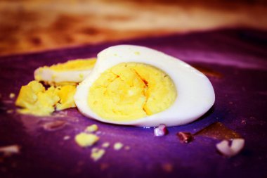 A boiled egg lies on a purple cutting Board. Egg, cut into slices
