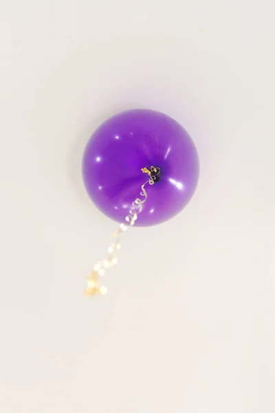 purple balloon with a gold ribbon is under the white ceiling
