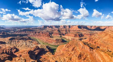 Dead Horse Point Eyalet Parkı ve Colorado Nehri 'ndeki ünlü kayalıkların ve kanyonların güzel panoramik manzarası güneşli bir günde mavi gökyüzü ve yaz aylarında manzaralı bulutlarla doludur.
