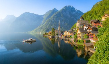 Ünlü eski kasabanın klasik panoramik manzarası. Hallstatt ve Alp 'in derin mavi gölü. Turist gemisi, güneşli bir yaz gündoğumu, Salzkammergut, Avusturya.