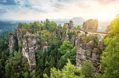 Saxon İsviçre Ulusal Parkı 'nda Elbe Sandstone dağları ile ünlü Bastei Köprüsü' nün güzel panoramik manzarası baharda güneş doğarken kara bulutlar, Saksonya, Almanya