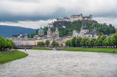 Tarihsel Salzburg şehrinin klasik panoramik manzarası ünlü Hohensalzburg Kalesi ve cennet gibi Salzach nehri ile güzel bir bahar günü, karanlık dramatik bir manzara ile, Salzburger Diyarı, Avusturya
