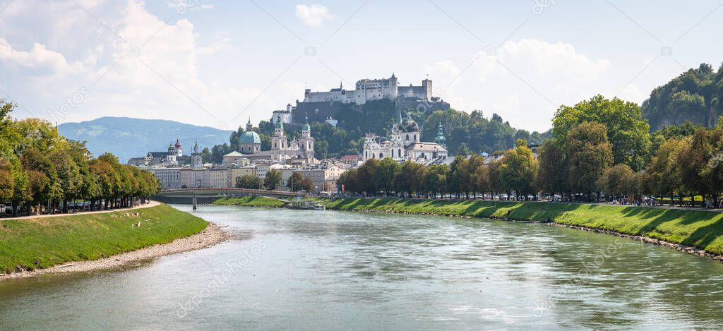 Classic panoramic view of the historic city of Salzburg with famous Hohensalzburg Fortress and beautiful Salzach river on a sunny day with blue sky and clouds in summer, Salzburger Land, Austria