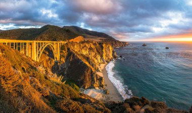 Yaz aylarında dramatik bulutlu bir gün batımında güzel altın akşam ışık dünyaca ünlü Highway 1 boyunca tarihi Bixby Creek Köprüsü Manzara panoramik görünümü, Monterey County, California, Abd