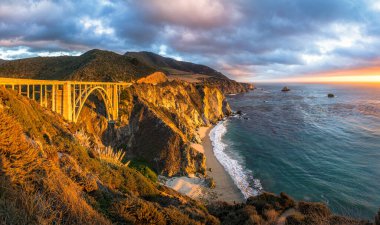 Scenic panoramic view of historic Bixby Creek Bridge along world famous Highway 1 in beautiful golden evening light at sunset with dramatic cloudscape in summer, Monterey County, California, USA clipart