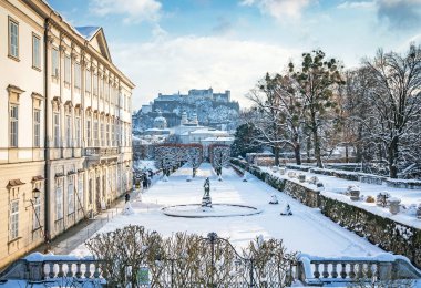 Tarihsel Salzburg şehrindeki ünlü Mirabell Gardens 'ın klasik manzarası. Hohensalzburg Kalesi altın bir akşam ışığında güneşli güzel bir günde, kışın mavi gökyüzü, Salzburger Diyarı, Avusturya