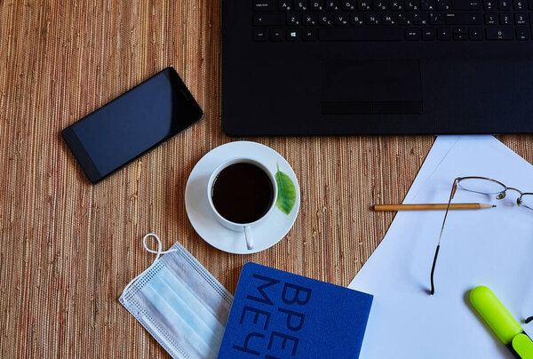 рабочее место с ноутбуком, защитная маска, синий ноутбук, кофе и смартфон
 