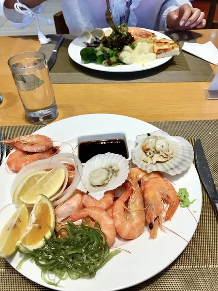 Variety of a buffet with oysters and king prawns with lemon on a table with a white tablecloth — Stock Photo, Image