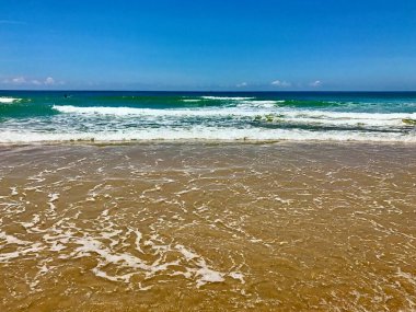 Zümrüt yeşili dalgaları ve mavi gökyüzüyle büyüleyici bir okyanus