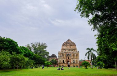 Delhi / Hindistan - 22 Eylül 2019: Yeni Delhi 'deki Lodi Gardens' ta insanlar Bada Gumbad camiinin önünde piknik yapıyorlar