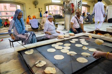 New Delhi / India - September 21, 2019: Volunteers preparing free food for visitors in the Gurdwara community kitchen (Langar hall) of Sri Bangla Sahib Gurudwara Sikh temple, New Delhi, India clipart