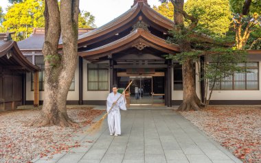 Tokyo / Japonya - 21 Nisan 2018: Meiji Tapınağı 'ndaki (Meiji Jingu) yaprakları süpüren keşiş, İmparator Meiji ve eşi Shoken' in Tokyo, Japonya 'daki tanrılaştırılmış ruhlarına adanmış Shinto türbesi.