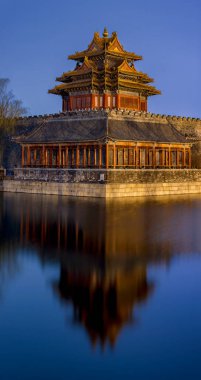 Northwestern tower of the Forbidden City Palace Museum reflecting in the water moat during still night in Beijing, China