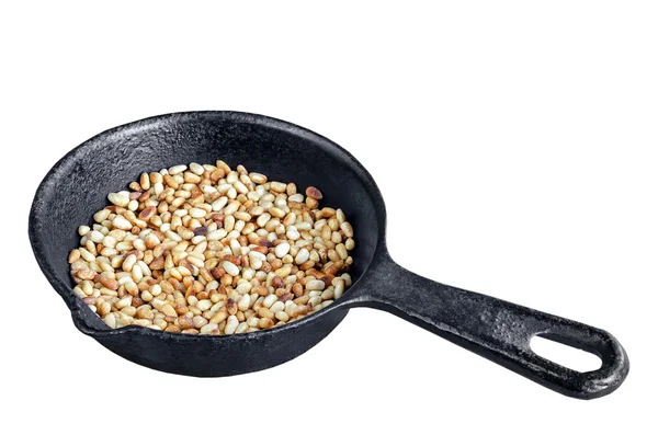 Toasted pine nuts in a frying pan, white background