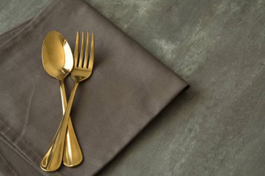 çatal ve kaşık altın platemat bezle parlak tablo kaya dokusu üzerinde