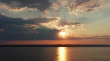 Güneşli bir günün altın gün batımının insansız hava aracı görüntüsü. Güneş ışınları güzel bulutların arasından geçiyor. İHA çekim günbatımı.