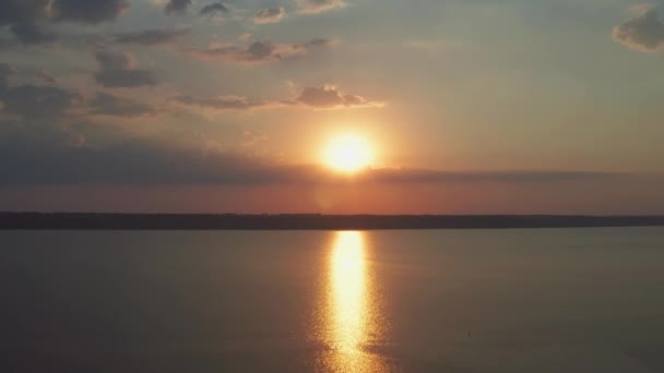 晴れた日のドローンカメラ黄金の夕日の空中ビュー 水の上に光のパスを持つ大規模な太陽ディスク 水の表面に小さな波 ドローン — ストック動画