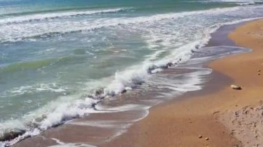Kumsalda kumlu bir sahile vuran gelgit dalgalarıyla kumsal. Hava aracı videosu