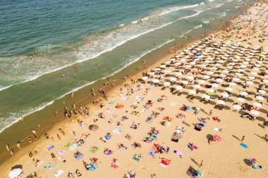 Bir İHA 'nın hava görüntüsü. Kumsalda turistler, güneşlikler ve odunlar